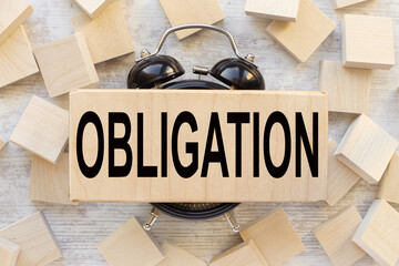 wooden block on table clock. text Obligations.