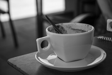 Gebrauchte Kaffeetasse auf einem Tisch, selektiver Fokus, Schwarzweißfotografie