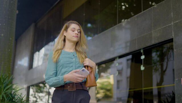 Successful confident trans gender businesswoman walking and using smarphone on the street
