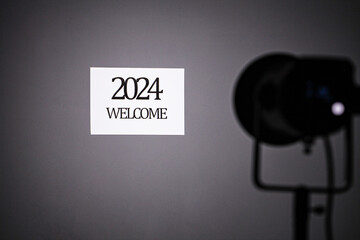 Welcome to 2024 words on the board. The concept of New Year in a studio where the light hits the blackboard, isolated on a gray background in a photography studio.