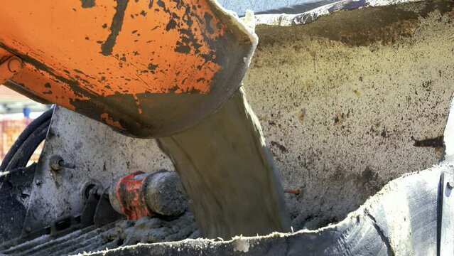 Truck Mixer Pouring Concrete into Concrete Pump. Concrete Pouring During Commercial Concreting Floors of Buildings at the Construction site. Construction Industry.