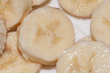Fototapeta na wymiar Background of ripe sliced banana slices, closeup. Food backdrop from fruit.
