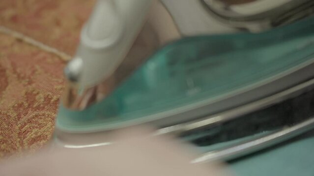 This POV video shows a stitcher's hand ironing and steaming the hemline of custom upholstery curtain panels.  