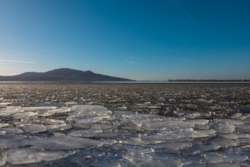 The lake landscape of Musov Czech Republic. View of Lake Musovske and Palava in the Czech Republic. Ice floes in the foreground. In the background, a TV transmitter and the ruins of Devicky Castle.