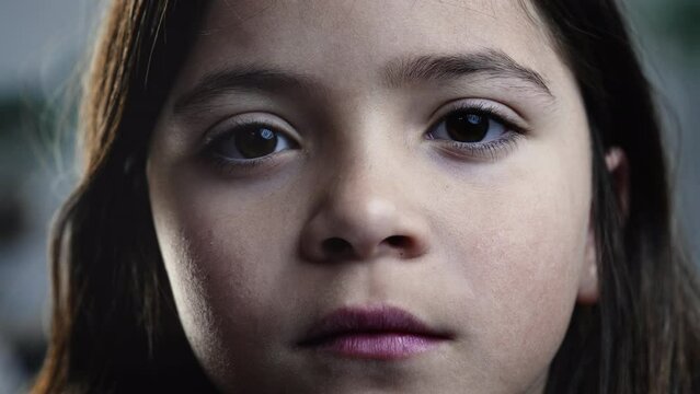 Child squinting in suspicion, tight macro close-up of little girl's eyes staring at camera inspecting with eyesight. Curious gaze listening attentively