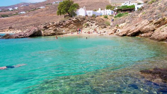 Paralia Agios Sostis wild and free beach in the north of Mykonos, Greece. Pristine bay with blue sea and crystal water, famous for naturism and Kiki's Tavern, peaceful and quiet. Gimbal cinematic