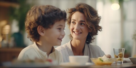 A woman is sitting next to a child at a table. This image can be used to depict a mother spending time with her child or for illustrating family activities