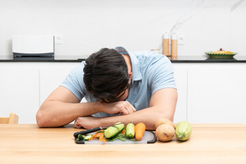 Fototapeta premium Tired and sad man peeling vegetables in the kitchen