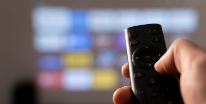 Karanlık odada TV'de multimedya video konsepti. Elinde uzaktan kumanda ile televizyon izleyen adam