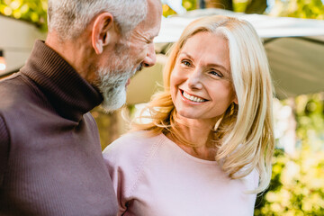 Cheerful senior couple looking at each other with passion and love in the park. Middle-aged spouses...