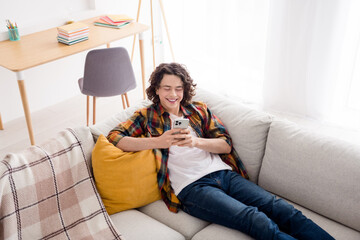 Photo of funky cheerful guy wear plaid shirt lying sofa texting instagram twitter telegram facebook...