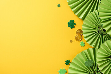Cheerful clover celebration: St. Paddy's delight. Top view photo of paper folding fans, trefoils, coins on yellow background with space for festive text