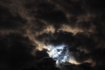 A partial solar eclipse of October 25, 2022 captured through moody dark clouds, the maximal phase...