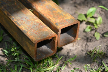 Building materials, equipment for construction and repair works. A long, thick, metal profile with a small amount of red rust located on the site.