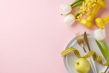 Energize your plate: Springtime diet tips for a vibrant you. Top view photo of plates, cutlery, apple, measuring tape, yellow dumbbells, mimosa, tulips on pastel pink background with advert area