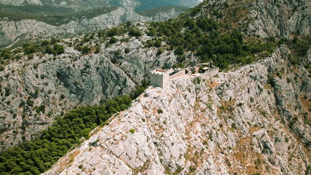 Ancient Fortress on Rocky Mountain in Croatia. The historical structure stands prominently atop limestone cliffs. Starigrad Fortica near Omis in Split-Dalmatia.