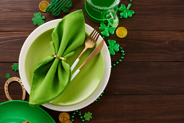 Celtic chic: St. Patrick's Day banquet in Irish splendor. Top view photo of plates, cutlery, leprechaun hat, party eyewear, green beer, trefoils, coins, beads on wooden background