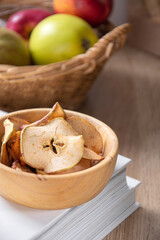 Naklejka na ściany i meble Dried apple slices on a wooden table in a wooden bowl