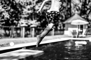 Selective focus on a swimming board as a young boy jumps into a pool. 