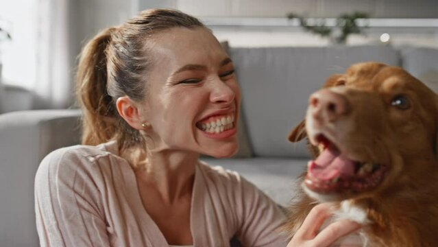 Happy pet owner laughing enjoying dog at home close up. Woman caressing animal