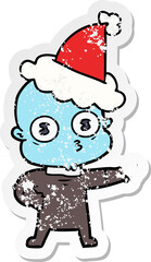 distressed sticker cartoon of a weird bald spaceman wearing santa hat