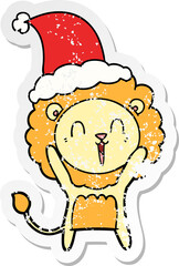 laughing lion distressed sticker cartoon of a wearing santa hat