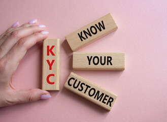 KYC - Know Your Customer. Wooden cubes with word KYC. Businessman hand. Beautiful pink background. Business and Know Your Customer concept. Copy space.