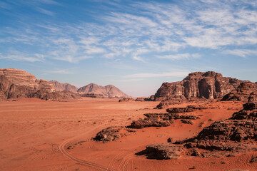 Fototapeta na wymiar Wadi Rum, Jordan, Scenic martian view of Arabic Middle Eastern desert against blue sky with red sand and rocks in foreground. Mountain in background. Copy space no people