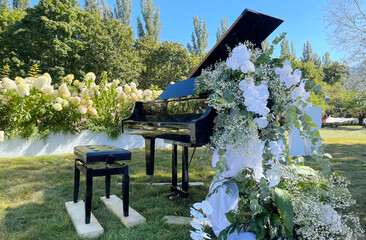Black grand piano with decorations in the park for performance
