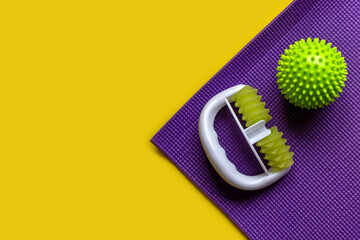 body massager on the exercise mat. yellow background copy space