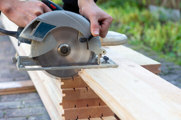 a carpenter cuts wooden floorboards with a circular saw