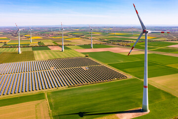 Aerial view of huge wind turbines between agricultural land and a solar park in rural area, Germany