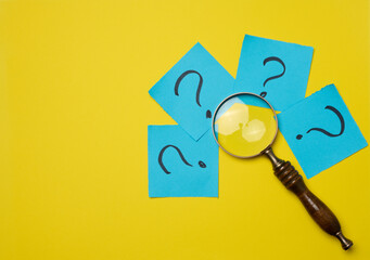 Drawn question marks on stickers and a magnifying glass, yellow background. Searching for truth and answering questions