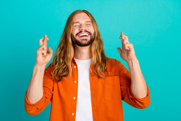 Portrait photo of young jesus christ handsome guy in orange shirt crossed fingers praying miracle...