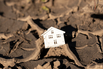 Model of a house and cracked earth depicting destruction after an earthquake. Place for text