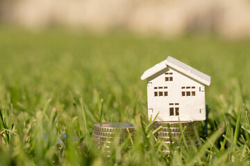 Stacks of coins on the lawn with house house, saving money to buy a house, financial plan mortgage loan concept.