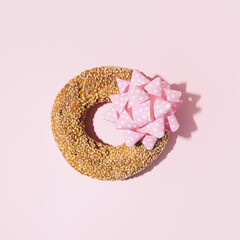 Sesame bagel decorated with a paper bow as a gift.