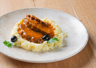 Meat in tomato sauce with potato garnish