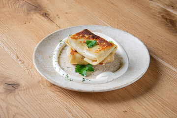 pancakes with creamy sauce on a light plate on a wooden table