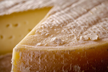 Cheese wheel close-up, a captivating shot showcasing the intricate textures and details of a large cheese wheel.