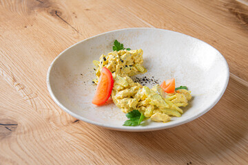 Scrambled omelette with tomato slices on a white plate