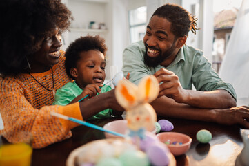 Cheerful multicultural family is painting easter eggs on easter saturday.
