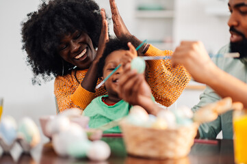 African american mother clapping because her son painted his first easter egg