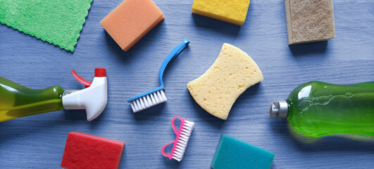 Banner background with cleaning products. Set of kitchen sponges, dish brushes, cleaning liquid, spray on a blue wooden table. Header template for website, blog, hardware store, cleaning company.