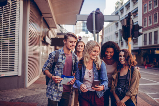 Diverse group of young people using a map and exploring the city on their vacation