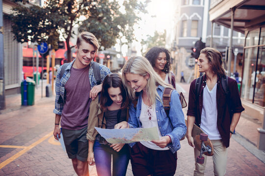 Diverse group of young people using a map and exploring the city on their vacation