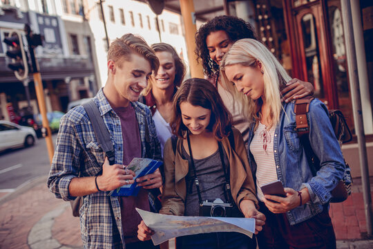 Diverse group of young people using a map and exploring the city on their vacation
