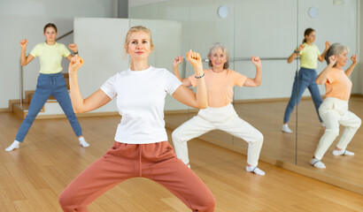Fototapeta premium Woman doing squats with her family on group fitness training in studio.