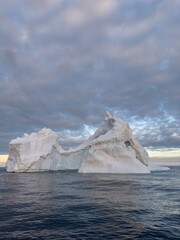 A huge high breakaway glacier drifts in the southern ocean off the coast of Antarctica at sunset,...
