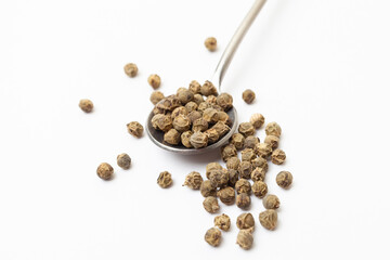 Green peppercorns in iron spoon on white background. Organic spice. Dry green pepper grain.